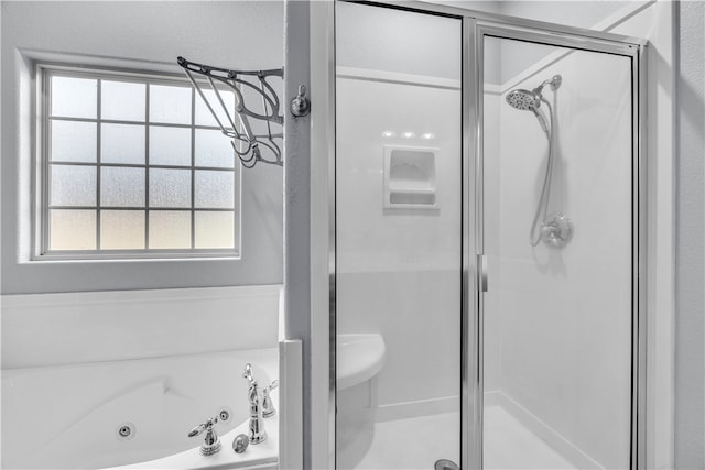 bathroom with a tub with jets, a shower stall, and a wealth of natural light