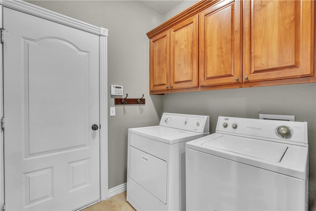 laundry room with washer and clothes dryer, cabinet space, and light tile patterned floors