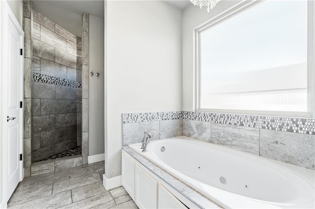 113 SE F St, Bentonville, AR 72712 - full bath featuring a healthy amount of sunlight, baseboards, a jetted tub, and tiled shower