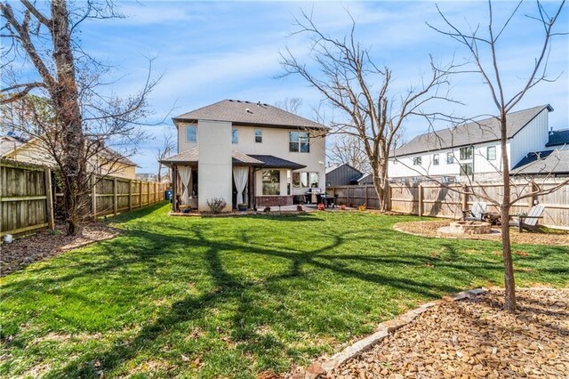113 SE F St, Bentonville, AR 72712 - back of house featuring a yard, a fenced backyard, roof with shingles, and an outdoor fire pit