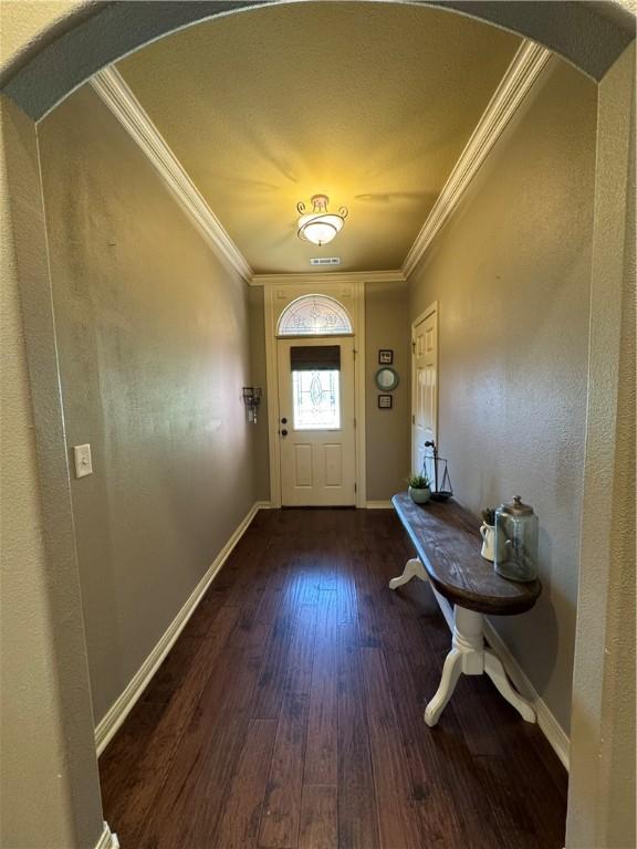 entrance foyer featuring crown molding, arched walkways, baseboards, and hardwood / wood-style flooring