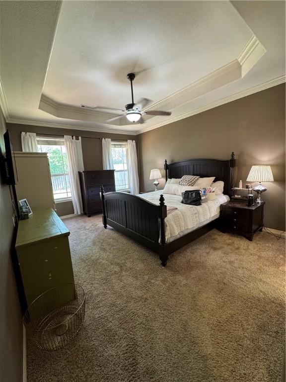 bedroom featuring crown molding, a ceiling fan, light carpet, and a tray ceiling