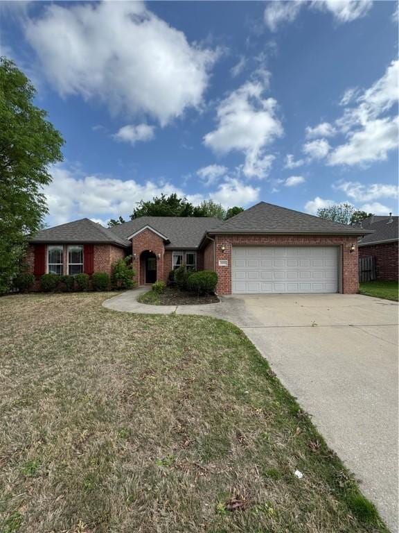single story home featuring an attached garage, driveway, brick siding, and a front yard