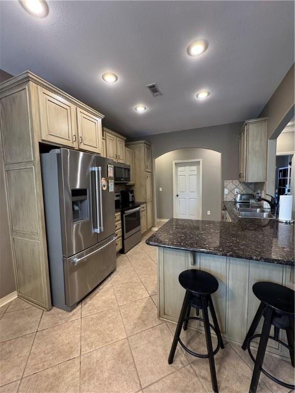 kitchen featuring a sink, arched walkways, stainless steel appliances, a peninsula, and visible vents
