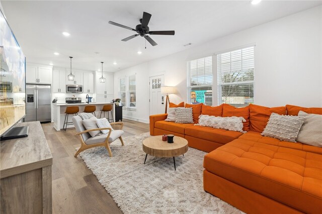 living area featuring light wood-style floors, ceiling fan, and recessed lighting