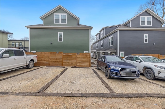 view of property exterior with fence and uncovered parking