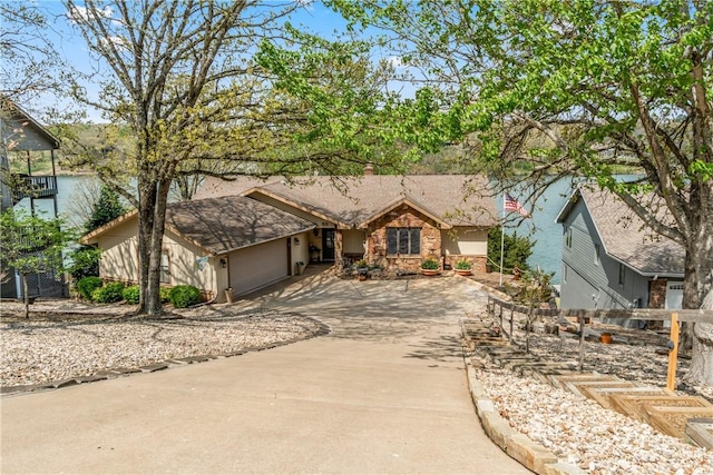 single story home with a garage, driveway, and stone siding