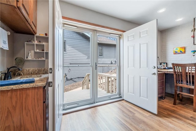 doorway to outside featuring recessed lighting, a sink, and light wood-type flooring
