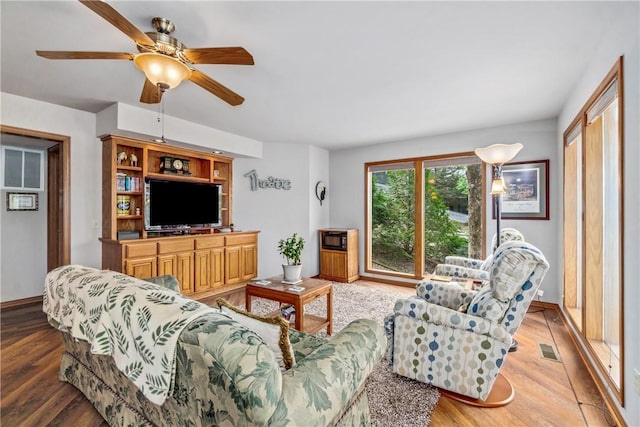 living area featuring visible vents, light wood-style flooring, ceiling fan, and baseboards
