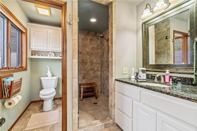 bathroom with vanity, a tile shower, and toilet
