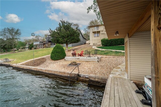 view of dock with a lawn and a water view