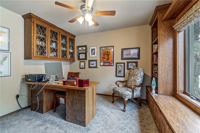 office area featuring light colored carpet, a ceiling fan, baseboards, and plenty of natural light