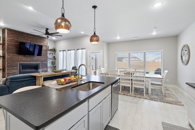 kitchen featuring dark countertops, open floor plan, a sink, and dishwasher