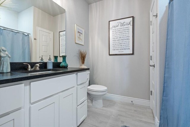 bathroom with vanity, baseboards, toilet, and wood finished floors