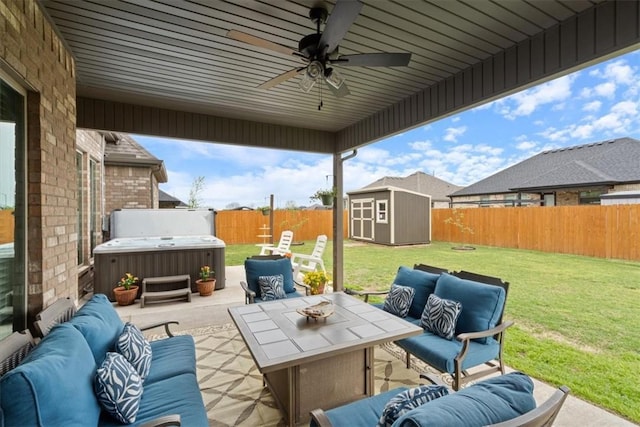 view of patio / terrace featuring a storage unit, a fenced backyard, a hot tub, and an outdoor living space