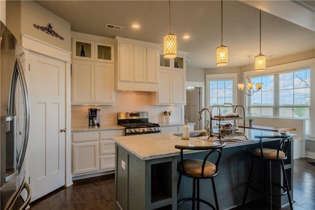 kitchen with stainless steel appliances, recessed lighting, dark wood-type flooring, visible vents, and a center island with sink