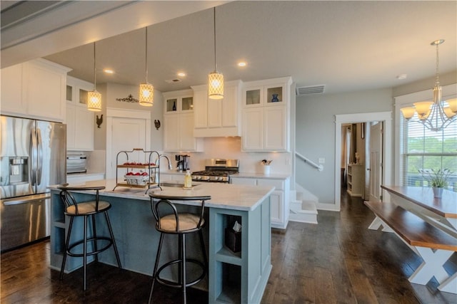 kitchen featuring visible vents, appliances with stainless steel finishes, a center island with sink, dark wood-style floors, and a chandelier
