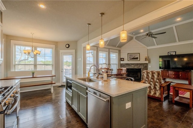 kitchen featuring appliances with stainless steel finishes, dark wood-style floors, a sink, a stone fireplace, and pendant lighting