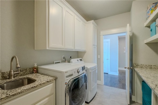 laundry area featuring cabinet space, separate washer and dryer, and a sink