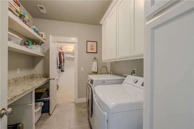 clothes washing area with cabinet space, separate washer and dryer, visible vents, and light tile patterned floors