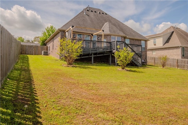 rear view of house with stairway, a deck, a fenced backyard, and a lawn