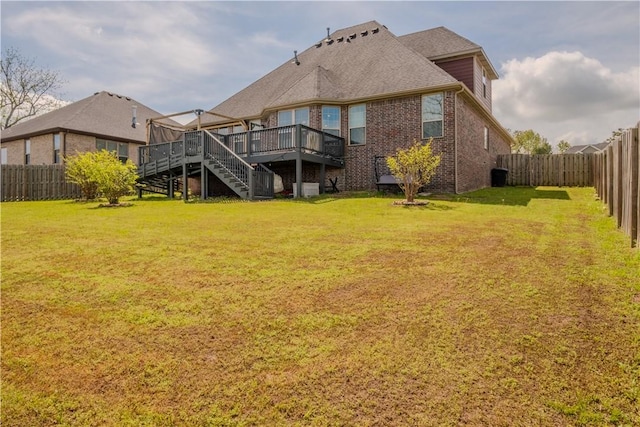 rear view of property featuring a fenced backyard, a yard, a wooden deck, and stairs