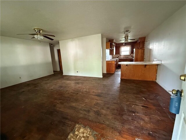 unfurnished living room featuring dark wood-type flooring and a ceiling fan