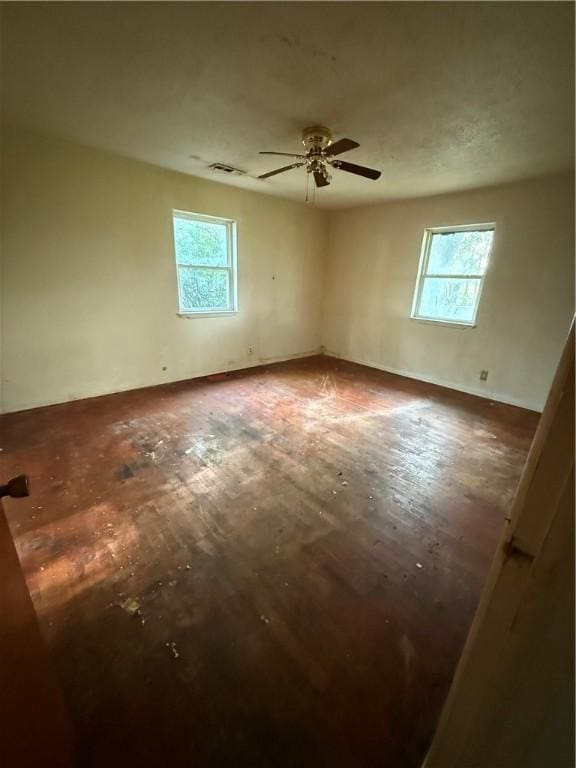 spare room with a ceiling fan, a wealth of natural light, and wood finished floors