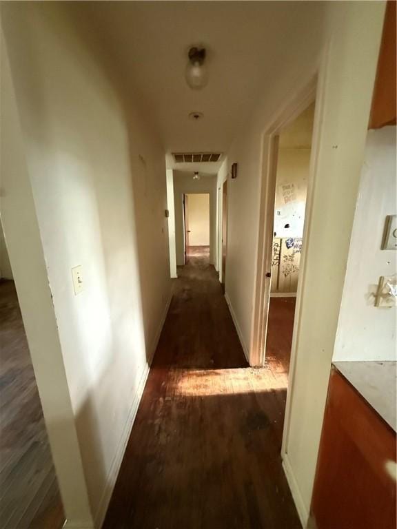 corridor featuring baseboards, visible vents, and wood finished floors
