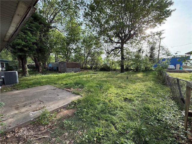 view of yard featuring an outdoor structure, fence, cooling unit, and a shed