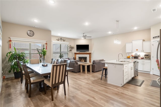 4311 SW Pawhuska St, Bentonville, AR 72713 - dining space featuring light wood-style flooring, a ceiling fan, recessed lighting, a tile fireplace, and visible vents