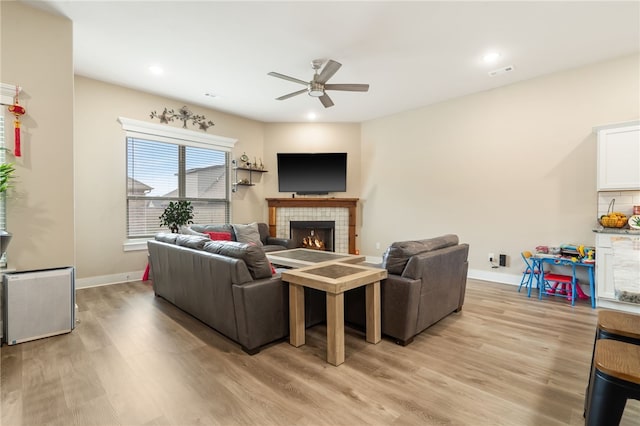 4311 SW Pawhuska St, Bentonville, AR 72713 - living room featuring light wood finished floors, a tiled fireplace, a ceiling fan, baseboards, and visible vents