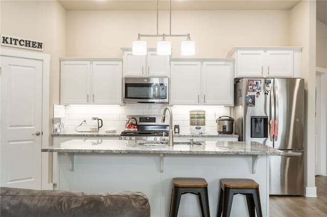 4311 SW Pawhuska St, Bentonville, AR 72713 - kitchen featuring decorative backsplash, a kitchen breakfast bar, appliances with stainless steel finishes, a sink, and white cabinetry