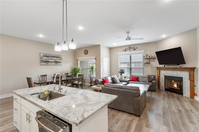 4311 SW Pawhuska St, Bentonville, AR 72713 - kitchen with ceiling fan, a tile fireplace, dishwasher, a sink, and light wood-style floors