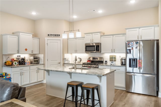 4311 SW Pawhuska St, Bentonville, AR 72713 - kitchen with decorative backsplash, a kitchen breakfast bar, a sink, stainless steel appliances, and white cabinetry