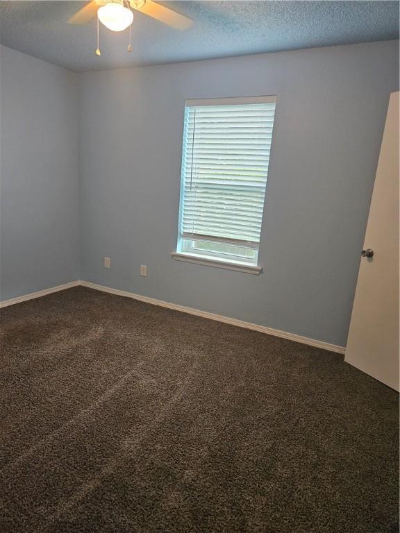 carpeted empty room with a textured ceiling, ceiling fan, and baseboards