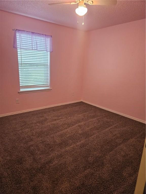 empty room featuring baseboards, a textured ceiling, ceiling fan, and dark colored carpet