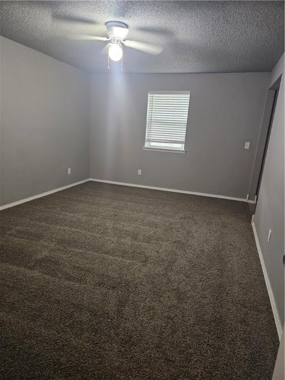 unfurnished room featuring baseboards, a textured ceiling, ceiling fan, and dark carpet
