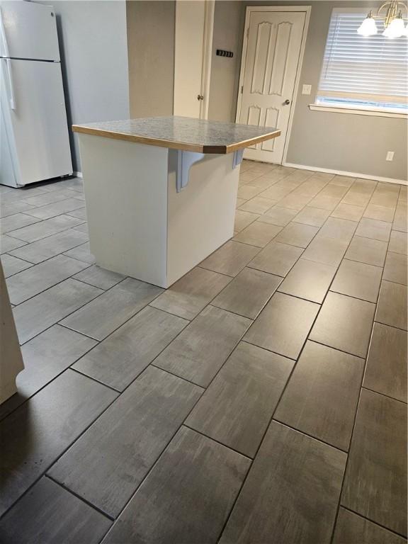 kitchen featuring a notable chandelier, light countertops, a breakfast bar area, a center island, and freestanding refrigerator