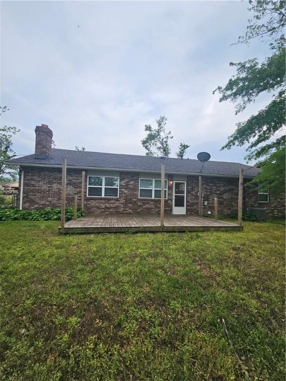 back of property featuring a yard, a deck, and a chimney