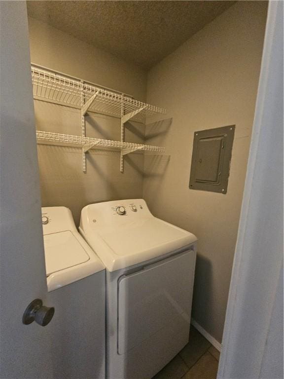 laundry room featuring dark tile patterned flooring, separate washer and dryer, and electric panel