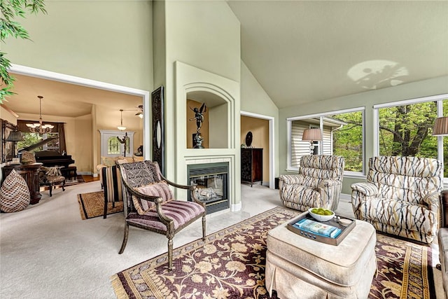 living area featuring a healthy amount of sunlight, high vaulted ceiling, a fireplace, and light colored carpet