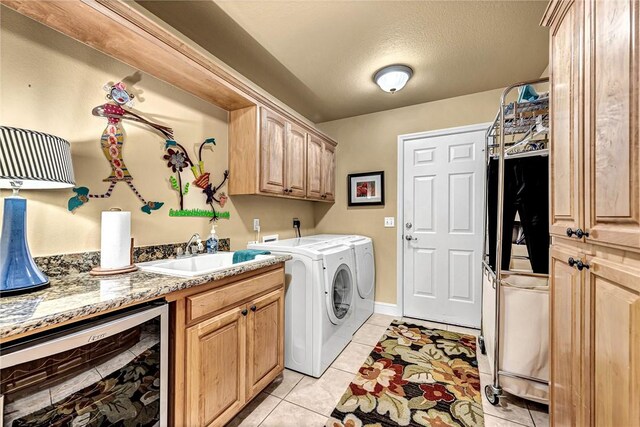 clothes washing area featuring cabinet space, washing machine and clothes dryer, a sink, light tile patterned floors, and wine cooler