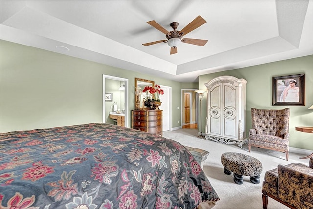 bedroom with light colored carpet, baseboards, and a tray ceiling