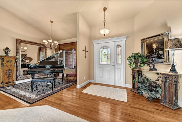 entrance foyer with baseboards, lofted ceiling, wood finished floors, and a notable chandelier