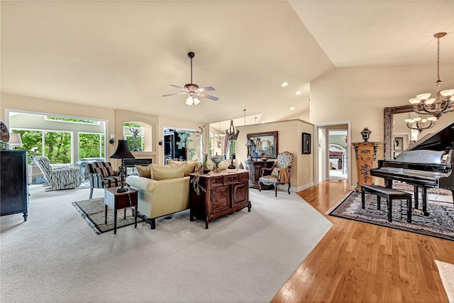 living area with vaulted ceiling, light wood-type flooring, baseboards, ceiling fan with notable chandelier, and recessed lighting