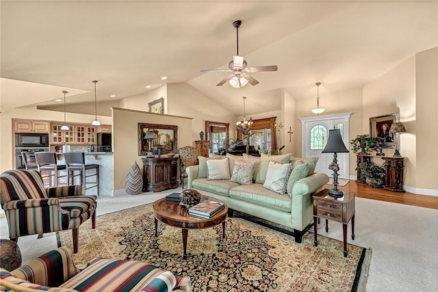 living area with ceiling fan with notable chandelier, baseboards, carpet, and vaulted ceiling