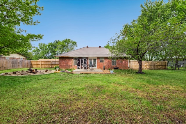 back of property featuring brick siding, a wooden deck, a fenced backyard, a yard, and metal roof