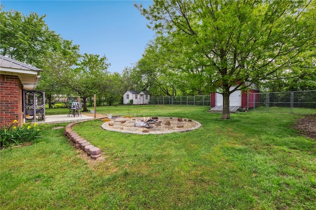 view of yard featuring a fenced backyard, an outbuilding, a storage shed, and an outdoor fire pit