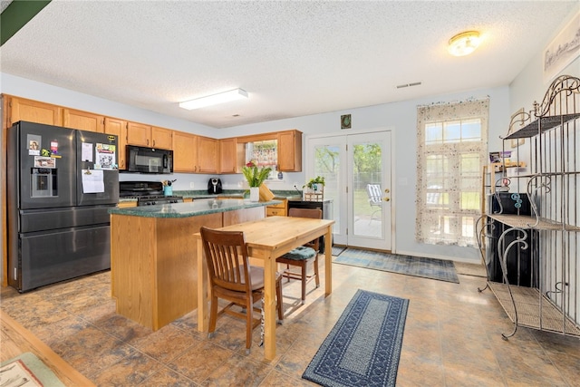 kitchen with black microwave, a textured ceiling, stove, a kitchen island, and refrigerator with ice dispenser